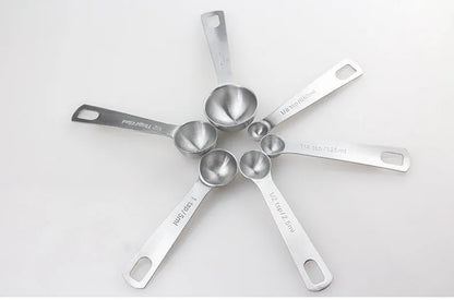 Set of six stainless steel measuring spoons connected by a silver D-ring, showing engraved measurement markings