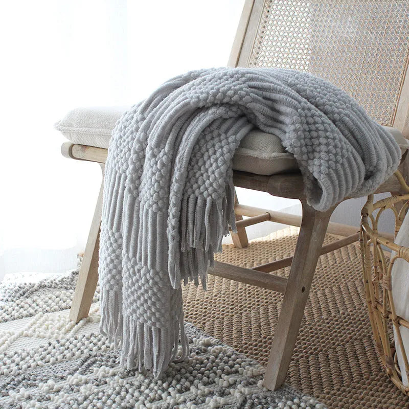 Nordic style knitted bubble texture blanket in light grey, draped over a sofa.