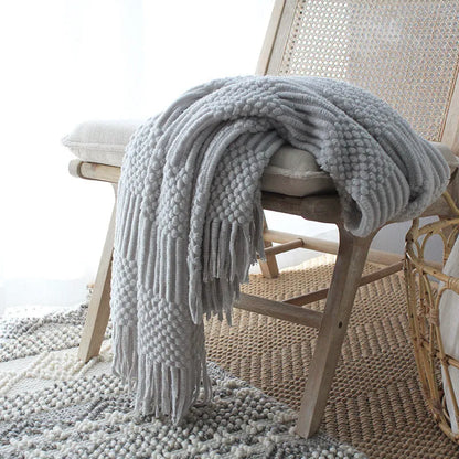Nordic style knitted bubble texture blanket in light grey, draped over a sofa.