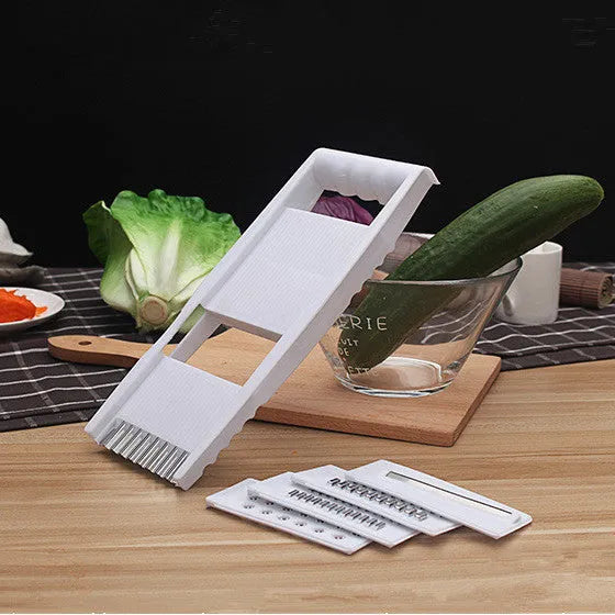 White five-piece stainless steel kitchen grater and vegetable slicer set with plastic hand guard