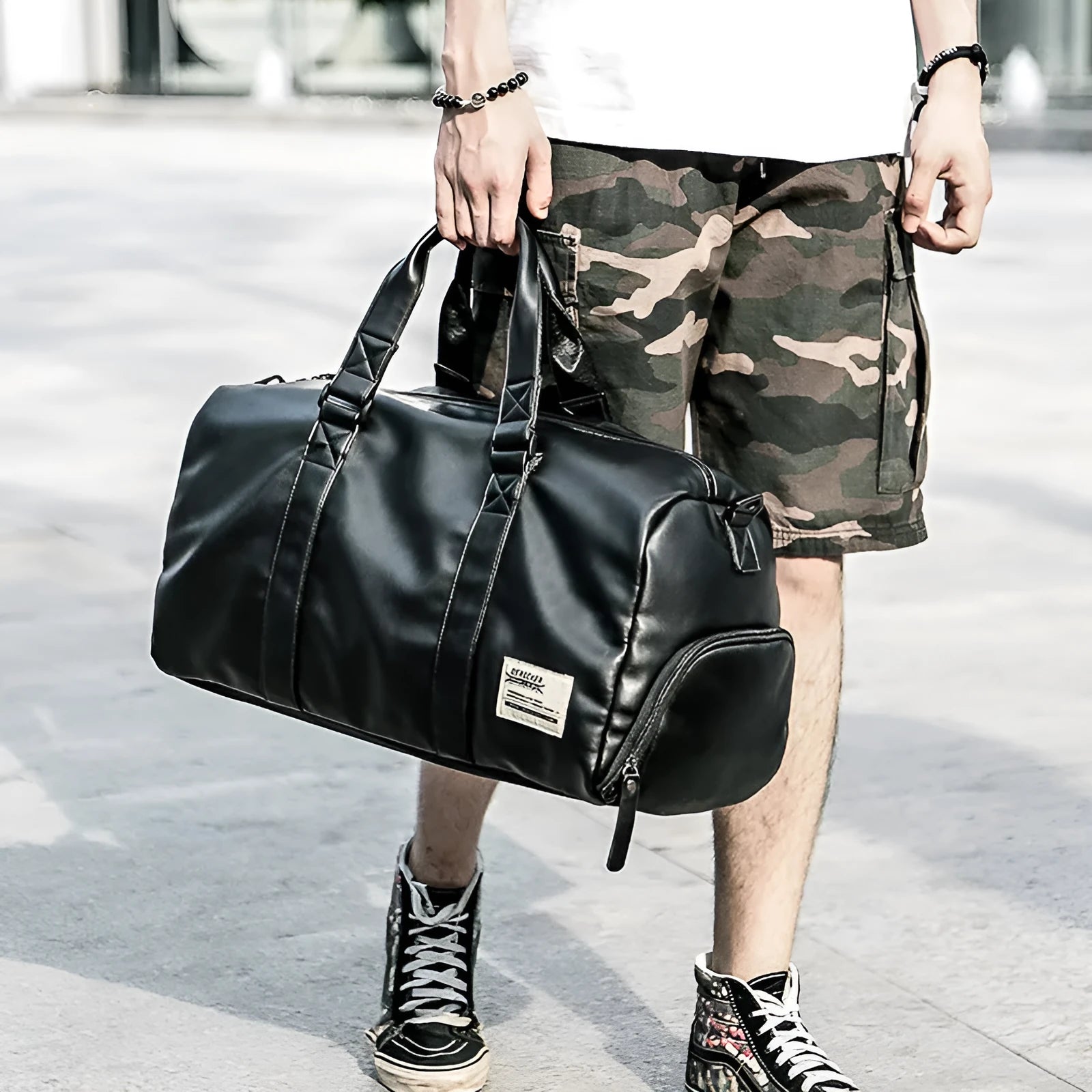 Large black waterproof PU leather sports duffel bag with multiple pockets, shown with a laptop and camera stored in its padded compartments.