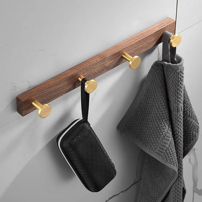 Black walnut wood clothes hooks with brass-finished aluminium frame in a 4-hook wall-mounted style