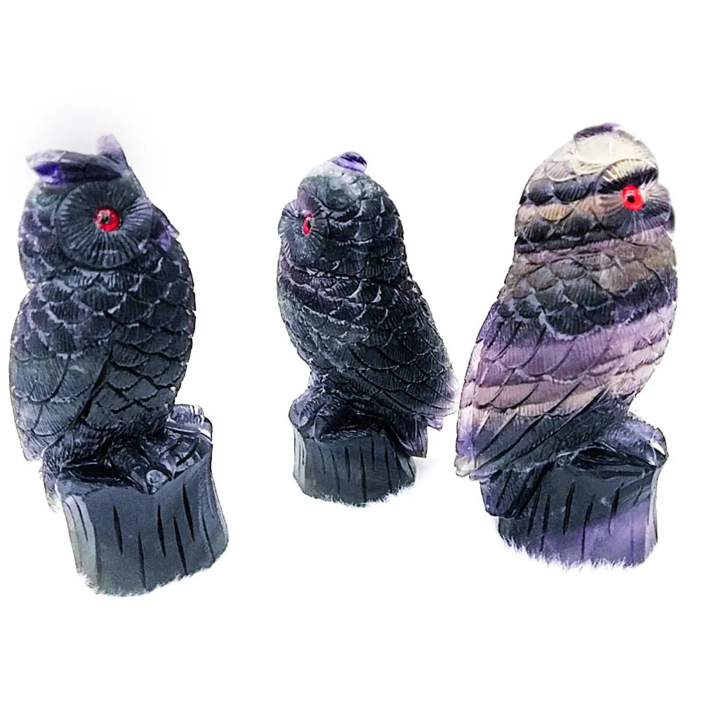 Hand-carved purple fluorite owl ornament on a neutral background, showing detailed carving and natural stone colour.