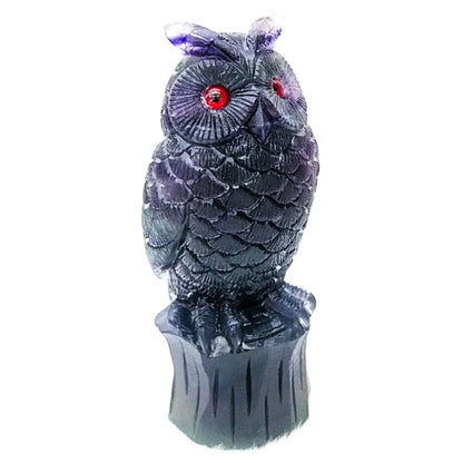 Hand-carved purple fluorite owl ornament on a neutral background, showing detailed carving and natural stone colour.