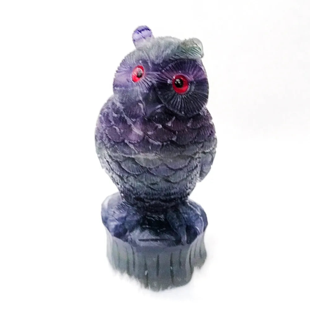 Hand-carved purple fluorite owl ornament on a neutral background, showing detailed carving and natural stone colour.