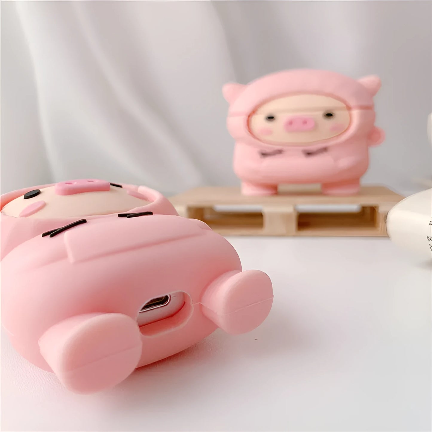 Pink silicone cartoon pig flip-case for AirPods with a metal carry hook attached.