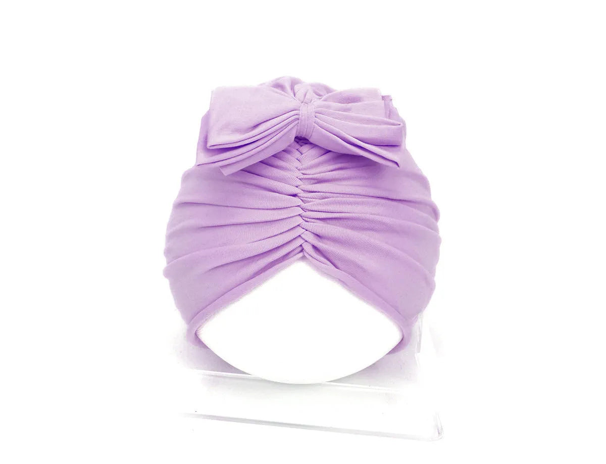 Soft acrylic knitted baby girl hat in a solid colour, shown fitting an infant.