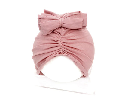 Soft acrylic knitted baby girl hat in a solid colour, shown fitting an infant.