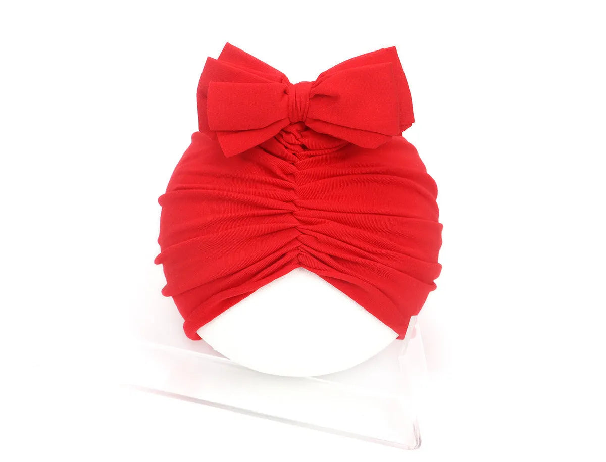 Soft acrylic knitted baby girl hat in a solid colour, shown fitting an infant.