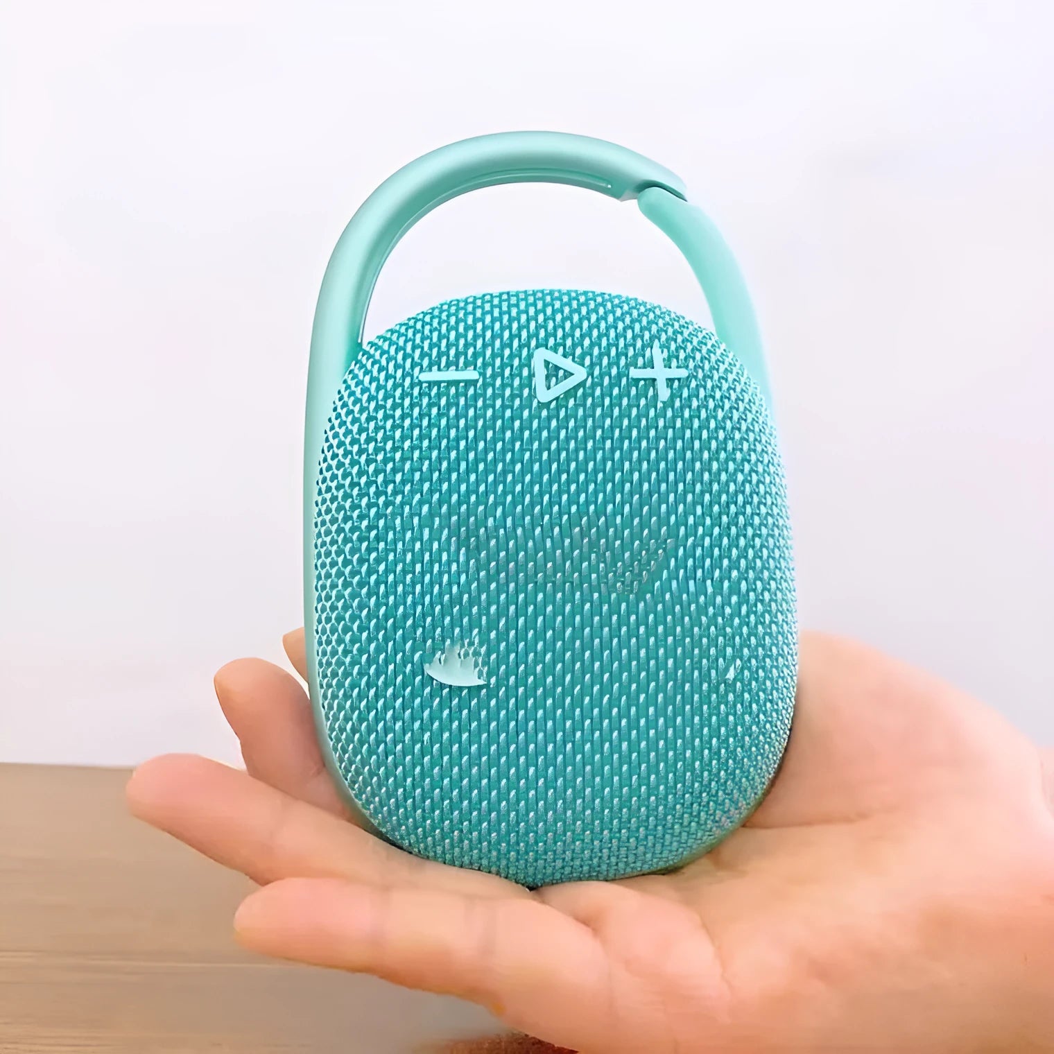 Compact 4th generation wireless Bluetooth speaker in silver grey colour with fabric grille on a wooden table.