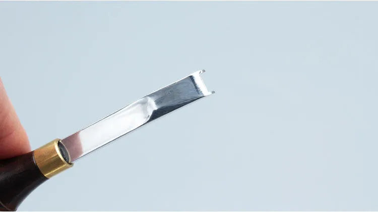 A leather-handled drum shovel wide shovel edge thinning knife on a workbench.