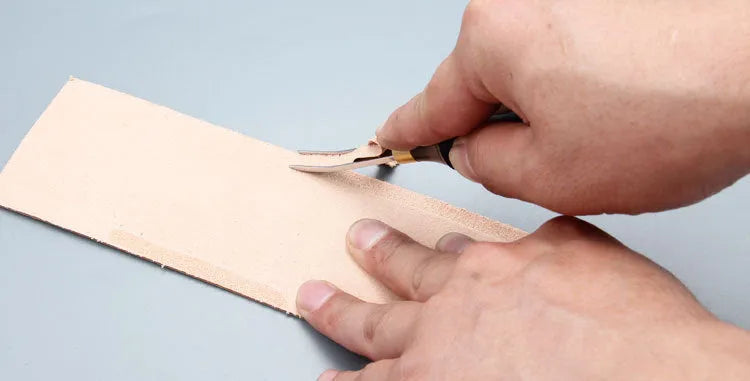 A leather-handled drum shovel wide shovel edge thinning knife on a workbench.