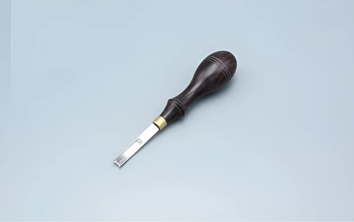 A leather-handled drum shovel wide shovel edge thinning knife on a workbench.