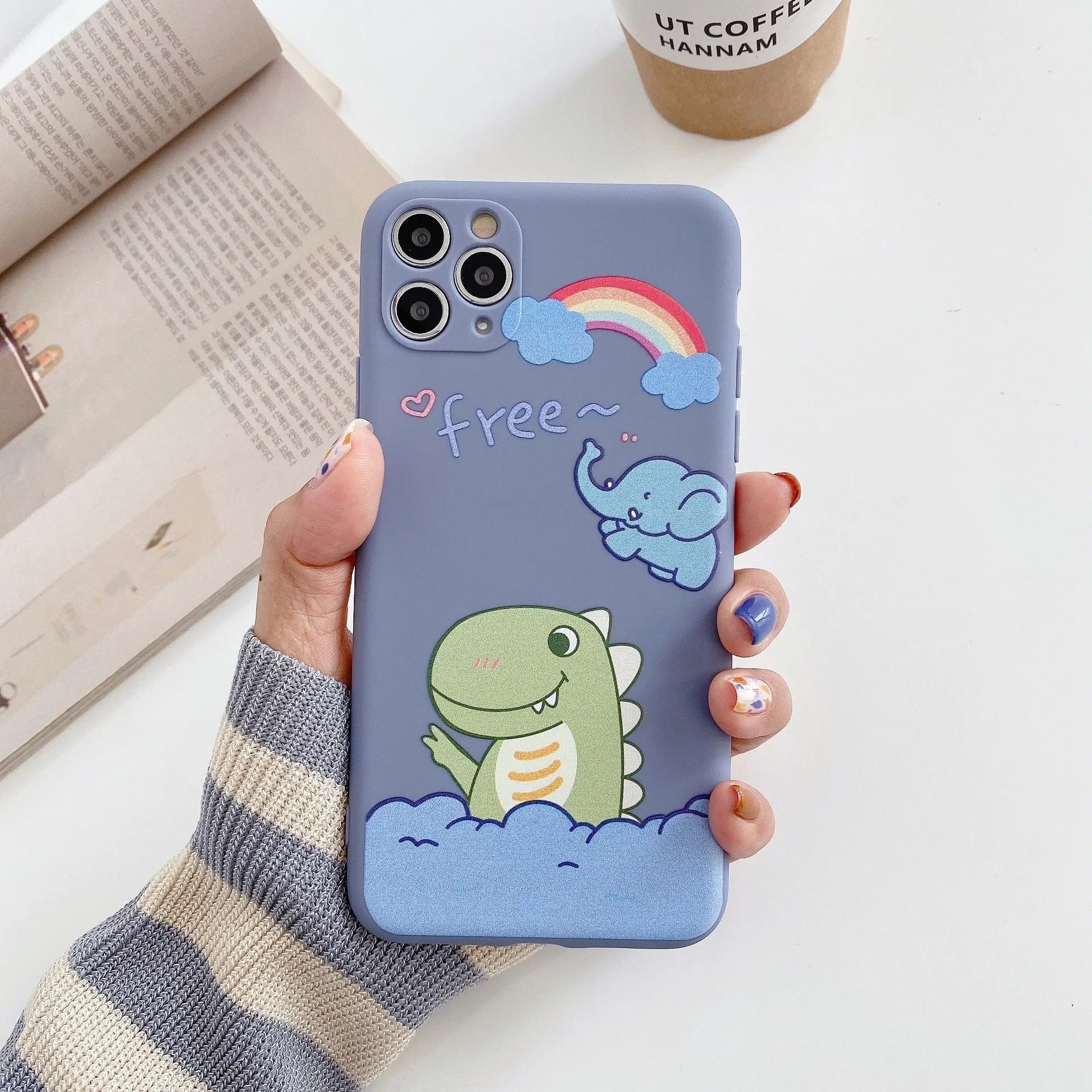 Blue frosted TPU iPhone case with a cartoon dinosaur print next to a pink case with a cat girl print.