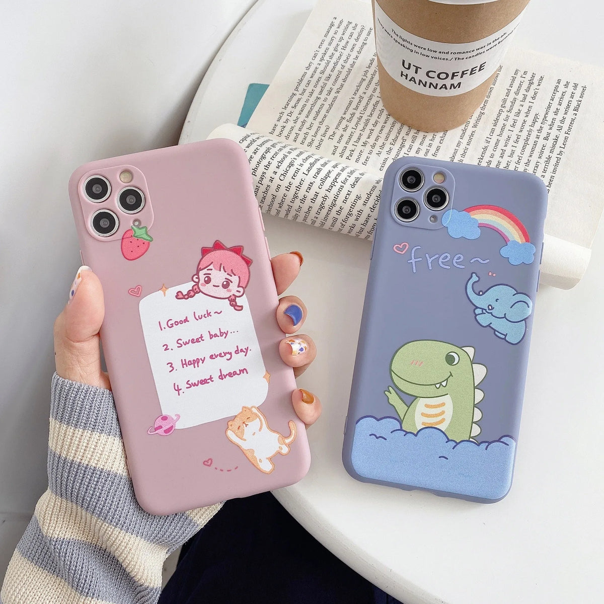 Blue frosted TPU iPhone case with a cartoon dinosaur print next to a pink case with a cat girl print.