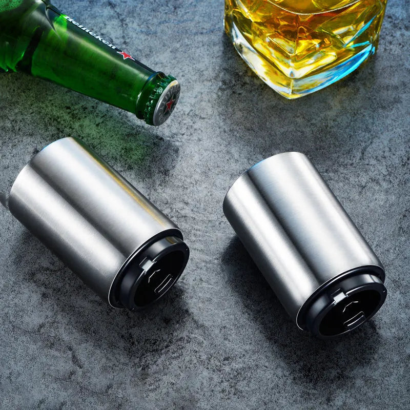 Stainless steel automatic bottle opener measuring 8.4 cm by 5.3 cm on a kitchen counter
