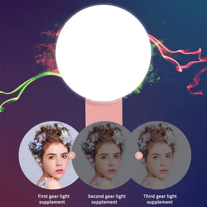 Small round white clip-on LED fill light attached to a mobile phone for selfies.