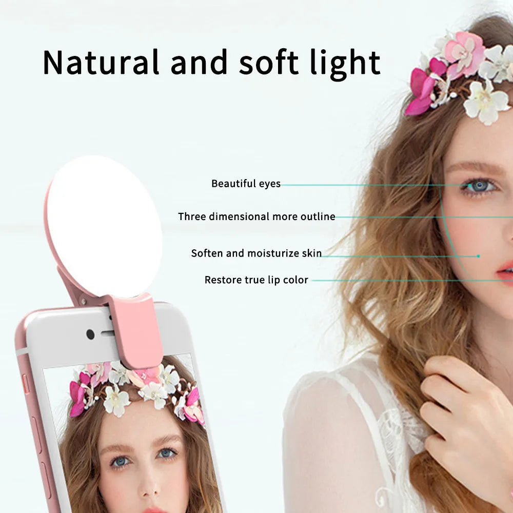 Small round white clip-on LED fill light attached to a mobile phone for selfies.