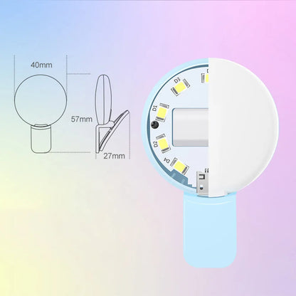 Small round white clip-on LED fill light attached to a mobile phone for selfies.