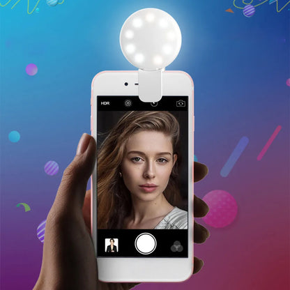 Small round white clip-on LED fill light attached to a mobile phone for selfies.