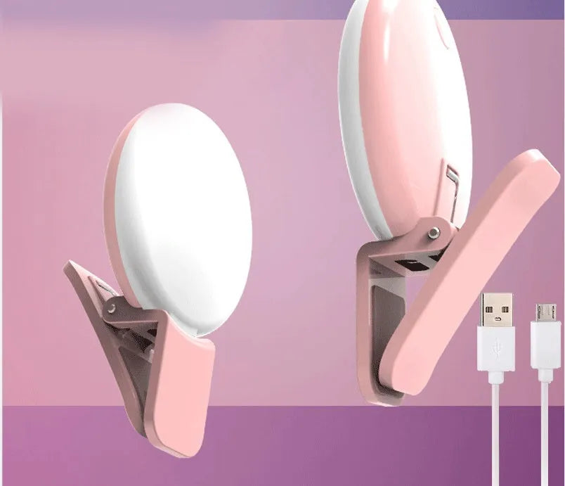 Small round white clip-on LED fill light attached to a mobile phone for selfies.