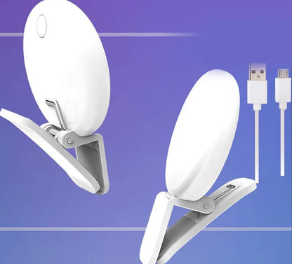 Small round white clip-on LED fill light attached to a mobile phone for selfies.
