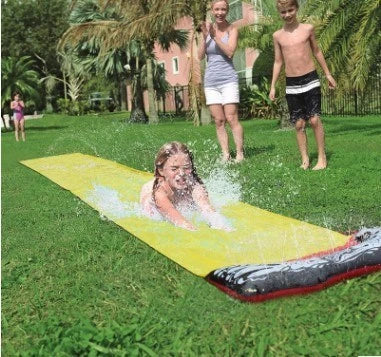 Children playing on a yellow inflatable water slide in a backyard garden