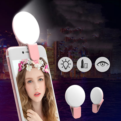 Small round white clip-on LED fill light attached to a mobile phone for selfies.