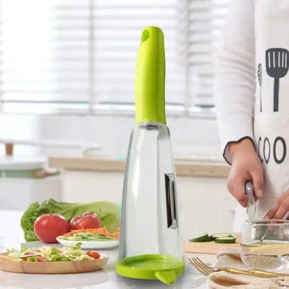 Green vegetable peeler with a transparent storage box attached, showing a stainless steel blade.
