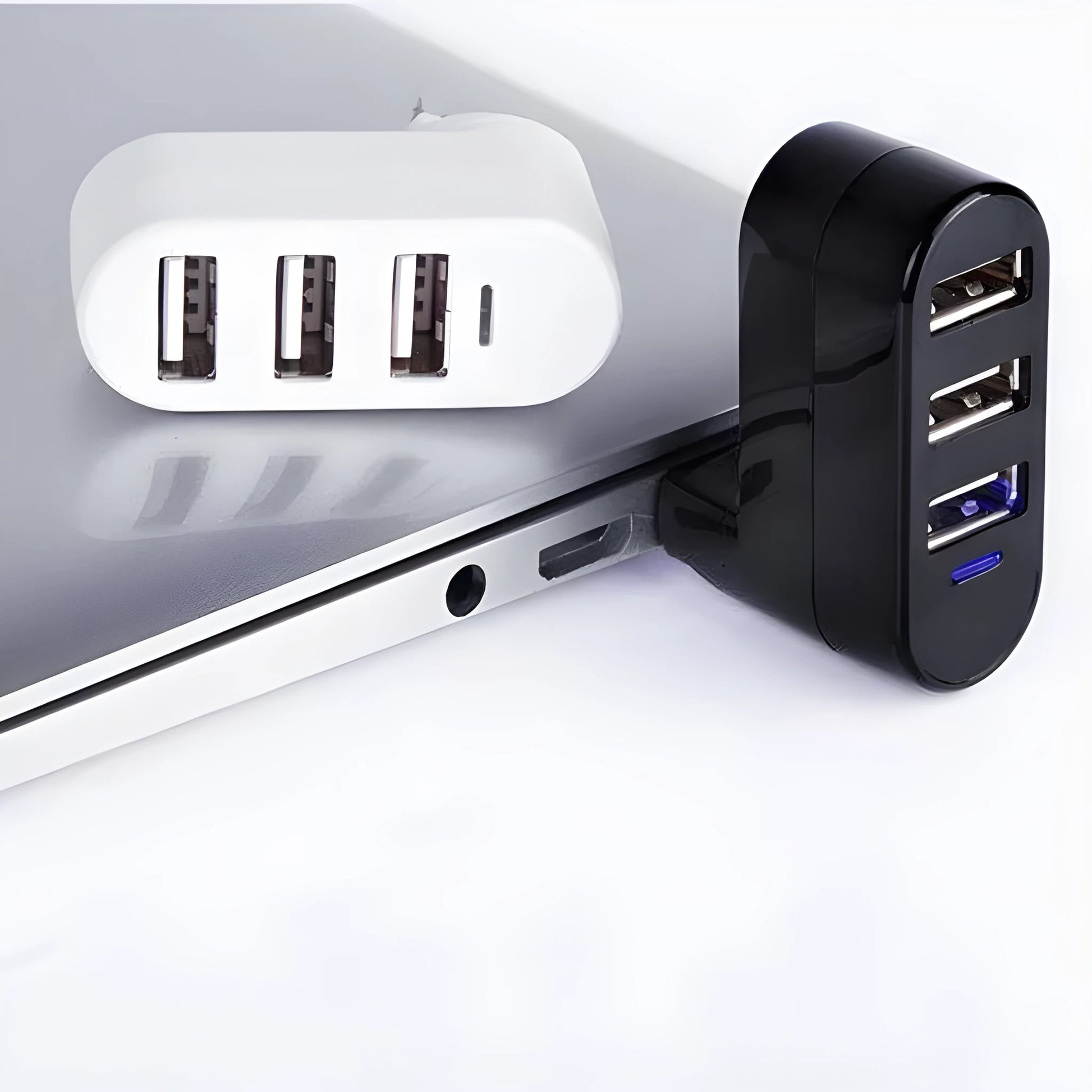 Black and white USB 2.0 hub splitter with spin colour casing on a desk next to a laptop.
