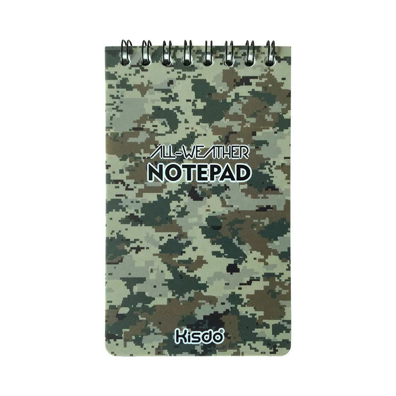 Spiral-bound waterproof notepad in camouflage colour, open on a wooden surface with a pen.