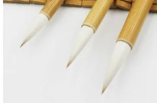 Three traditional Chinese calligraphy brushes with bamboo handles and wool bristles in large, medium, and small sizes.