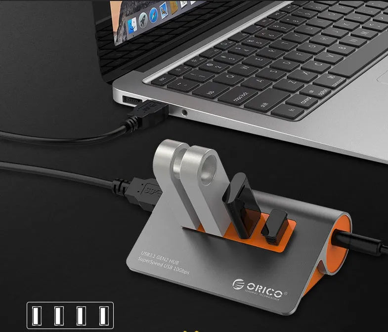 Dark grey and orange aluminium laptop hub with four USB ports, a blue LED light, and a detached cable.