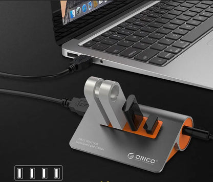Dark grey and orange aluminium laptop hub with four USB ports, a blue LED light, and a detached cable.