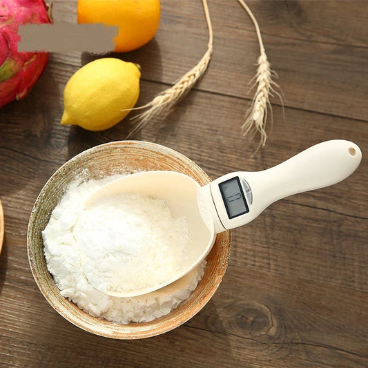 Compact digital kitchen scale with sleek beige design, showing four measurement units and detachable spoon for convenient use in home baking and cooking.