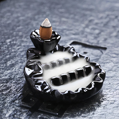 Black ceramic backflow incense burner creating waterfall smoke with sandalwood aroma