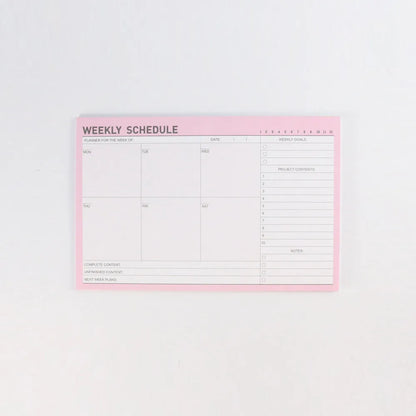 Paper brick desk organiser pad showing weekly and monthly planning sections with pink and green mixed colours