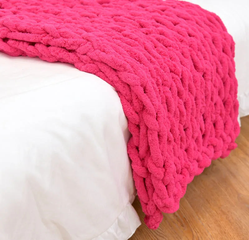 Handmade chunky knitted chenille blanket with cable stitching on sofa
