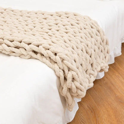Handmade chunky knitted chenille blanket with cable stitching on sofa
