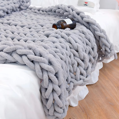 Handmade chunky knitted chenille blanket with cable stitching on sofa