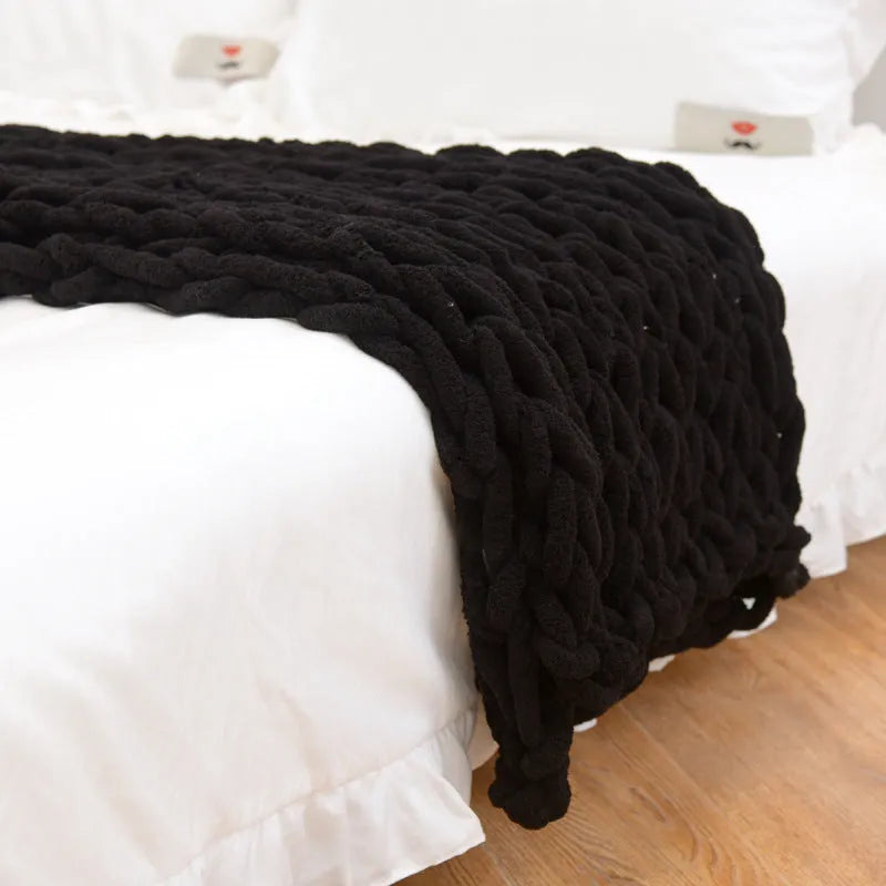 Handmade chunky knitted chenille blanket with cable stitching on sofa