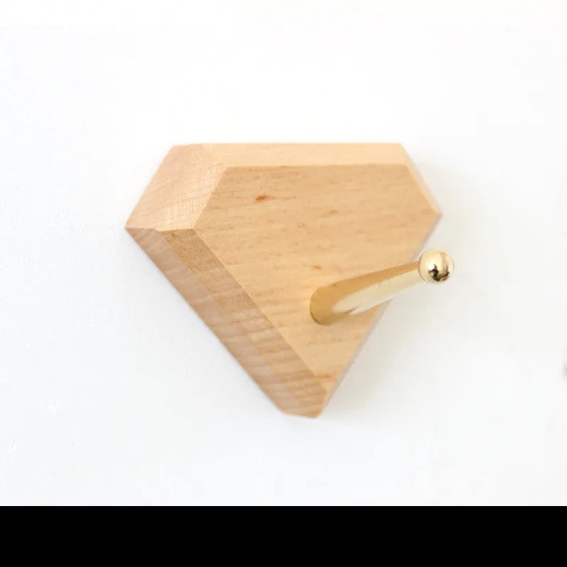 Natural beech wood adhesive wall hook in a capsule shape, shown on a wall for damage-free hanging.
