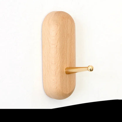 Natural beech wood adhesive wall hook in a capsule shape, shown on a wall for damage-free hanging.