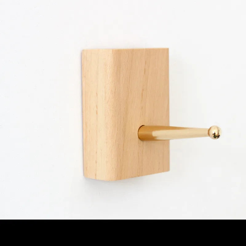 Natural beech wood adhesive wall hook in a capsule shape, shown on a wall for damage-free hanging.