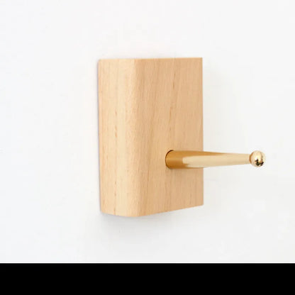 Natural beech wood adhesive wall hook in a capsule shape, shown on a wall for damage-free hanging.