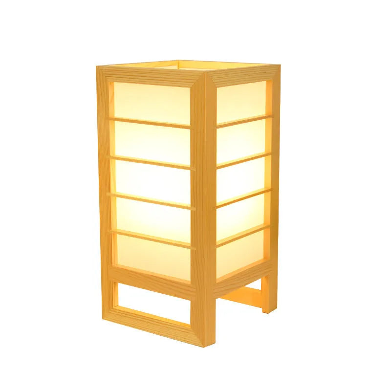 Minimalist solid bamboo wood bedside lamp with a tatami-inspired base and a fabric lamp shade on a wooden table.