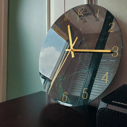 Round silent wall clock with acrylic glass dial, shown in a living room setting.