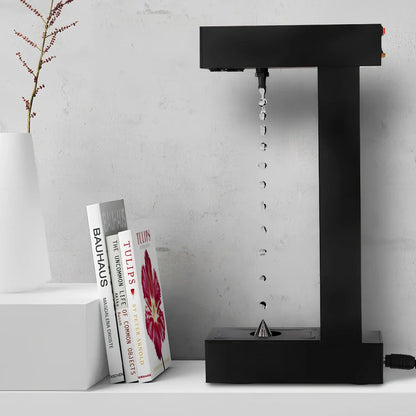 Obsidian black anti-gravity floating sand drop table lamp with geometric hourglass and LED glow