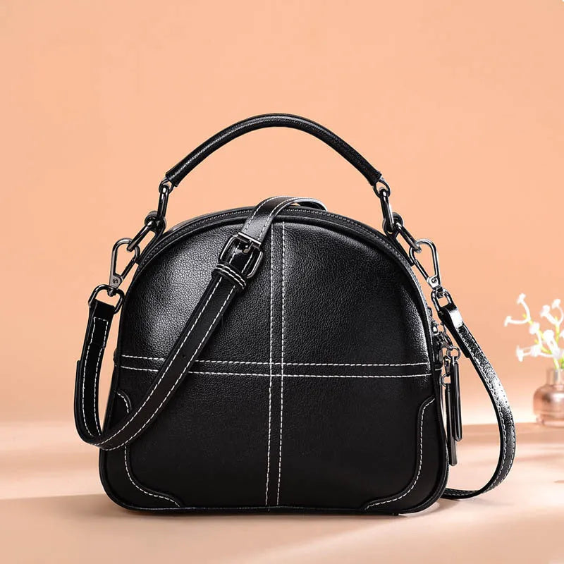 Round leather handbag with soft double handles and zipper closure in wine red colour