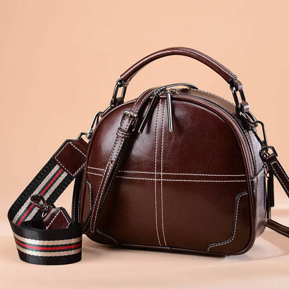 Round leather handbag with soft double handles and zipper closure in wine red colour